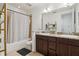 Well-lit bathroom featuring double sinks with granite countertop and a shower/tub combo with a patterned curtain at 10423 Belfry Cir, Orlando, FL 32832