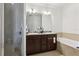 Well-lit bathroom with a double vanity, bathtub, and tiled shower stall with glass door at 10423 Belfry Cir, Orlando, FL 32832