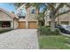 Elegant townhome featuring a stone facade, private balconies, two-car garage and a brick paved driveway at 10423 Belfry Cir, Orlando, FL 32832