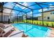Beautiful pool area featuring a screened enclosure, lounge chairs, and well-maintained landscaping at 1512 Mumbai Way, Kissimmee, FL 34747