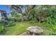 Lush backyard with stone table and seating nestled amidst mature trees and vibrant foliage at 1606 Orangewood Ave, Orlando, FL 32806