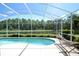 Screened-in pool area features a relaxing hammock, lush greenery, and tranquil views of a lake at 1764 Carillon Park Dr, Oviedo, FL 32765