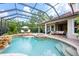 Stunning screened-in pool and spa with waterfall feature, lush landscaping, and covered patio at 2000 Bloomsbury Run, Lake Mary, FL 32746