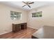 Bedroom featuring hardwood floors, two windows, ceiling fan, and vintage wooden desk at 2151 Conifer Ave, Winter Park, FL 32792