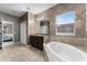 This primary bathroom features a soaking tub, granite counters, decorative wallpaper, and natural light at 2275 Pearl Cider St, Orlando, FL 32824