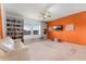 This versatile room features built-in shelving, a comfortable couch, and an orange accent wall with a TV at 2275 Pearl Cider St, Orlando, FL 32824