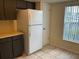 Functional kitchen featuring a white refrigerator, dark cabinets, and tiled flooring at 228 Everest Pt # 108, Casselberry, FL 32707