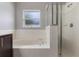 The bathroom features a soaking tub, a window with natural light, and a glass-enclosed shower at 2360 Brewerton Ln, Orlando, FL 32824