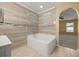 Elegant bathroom with a soaking tub, tile surround, and a view to the bedroom through an arched door at 2725 White Magnolia Loop, Clermont, FL 34711