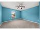 Inviting blue bedroom with plush carpeting, a ceiling fan, and a bright window at 2725 White Magnolia Loop, Clermont, FL 34711