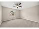 Empty bedroom featuring neutral carpet, ceiling fan, and a window overlooking trees at 2725 White Magnolia Loop, Clermont, FL 34711