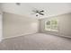 Bright, carpeted bedroom featuring neutral walls, a ceiling fan, and a window for natural light at 2725 White Magnolia Loop, Clermont, FL 34711