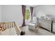 Cozy Bedroom featuring a neutral color palette, crib, and rocking chair by the window at 38 Jett Loop, Apopka, FL 32712