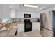 Bright kitchen featuring white cabinets, stainless steel refrigerator, and modern black appliances at 4217 Ilene Ct, Orlando, FL 32806
