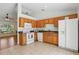 Sunlit kitchen with light-brown cabinetry, white appliances, and a seamless view into the living area at 608 Swanson St, Groveland, FL 34736