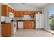 Functional kitchen features light-brown cabinetry, white appliances and tile floors, inviting culinary creativity at 608 Swanson St, Groveland, FL 34736