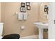Neutral-toned half bath with a pedestal sink, round mirror, and decorative wall art at 901 Grovesmere Loop, Ocoee, FL 34761