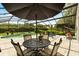Outdoor patio with a table, chairs and an umbrella, overlooking the pool and manicured backyard through the screen at 901 Grovesmere Loop, Ocoee, FL 34761