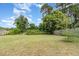 Lush backyard with expansive green lawn, mature trees, and a cozy swing set, perfect for outdoor enjoyment at 9355 Telfer Run, Orlando, FL 32817