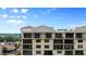 Multi-story building with multiple balconies and windows, set against a backdrop of blue skies and lush greenery at 111 E Monument Ave # 801, Kissimmee, FL 34741
