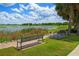 Scenic park view with benches, grass, palm trees, and a lake under a sunny sky at 111 E Monument Ave # 801, Kissimmee, FL 34741
