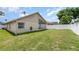 A well kept backyard with green grass, a white fence and a view of the house and sunroom at 11715 Sindlesham Ct, Orlando, FL 32837