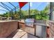Screened-in outdoor kitchen area featuring a stainless steel grill and granite countertops, perfect for entertaining at 13478 Summer Rain Dr, Orlando, FL 32828