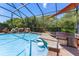 Inviting screened pool with waterfall feature, rock grotto, in-pool seating and outdoor kitchen at 13478 Summer Rain Dr, Orlando, FL 32828