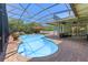 Inviting screened pool with waterfall feature, rock grotto, in-pool seating, and covered patio area at 13478 Summer Rain Dr, Orlando, FL 32828