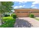 Attached garage with brick paver driveway and manicured landscaping with green shrubs at 14897 Evergreen Oak Loop, Winter Garden, FL 34787