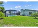 Back yard with green grass, in-ground pool with screened enclosure and back of home at 1930 Aster Dr, Winter Park, FL 32792
