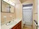 Bathroom with wallpaper, wood cabinets, and shower/tub combo with seashell-themed shower curtain at 2020 Cocos Ct, Winter Park, FL 32792