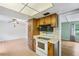 A kitchen with white appliances, wood cabinets, and an opening to the dining/living area at 2020 Cocos Ct, Winter Park, FL 32792