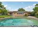 Backyard view of the in-ground pool with tile border, brick house, and lush landscaping at 2020 Cocos Ct, Winter Park, FL 32792