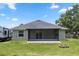 Back of the house featuring a screened-in patio with a spacious yard and fire pit at 2305 Ascot Ave, Orlando, FL 32833
