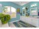 Bright bathroom featuring dual sinks, white cabinetry, large window, and vibrant turquoise walls at 2440 Pawtucket Pass, Mount Dora, FL 32757