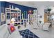 Bright living room featuring open shelving, white wicker furniture, and a blue accent wall at 2440 Pawtucket Pass, Mount Dora, FL 32757