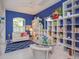Living room with blue walls, a white sofa, and white bookshelves at 2440 Pawtucket Pass, Mount Dora, FL 32757