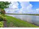 Scenic view of a tranquil pond bordered by lush greenery and landscaping on a partly cloudy day at 2440 Pawtucket Pass, Mount Dora, FL 32757
