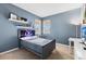 Cozy bedroom with a blue accent wall, a gray bed with shelves, and bright natural lighting at 3279 Canna Lily Pl, Clermont, FL 34711