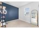 A simplistic bedroom featuring blue accent wall, large window, and modern décor and neutral carpet at 3279 Canna Lily Pl, Clermont, FL 34711