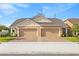 A well-maintained tan house with a brick driveway and a 2 car garage at 3279 Canna Lily Pl, Clermont, FL 34711