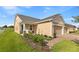 A well-maintained tan house with a green lawn, side entry and a 2 car garage at 3279 Canna Lily Pl, Clermont, FL 34711