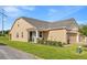 A well-maintained tan house with a green lawn, side entry and a 2 car garage at 3279 Canna Lily Pl, Clermont, FL 34711