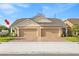A well-maintained tan house with a brick driveway and a 2 car garage at 3279 Canna Lily Pl, Clermont, FL 34711