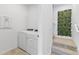 Bright laundry room featuring white front-load machines and a decorative greenery wall accent on the stairs at 3279 Canna Lily Pl, Clermont, FL 34711
