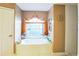 A luxurious bathroom featuring a large soaking tub under a window with decorative curtains at 4633 Sw 103Rd Pl, Ocala, FL 34476