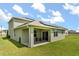 Back exterior featuring a covered patio with views of the lawn, a green exterior, and solar panels at 5226 Mahogany Dr, Mount Dora, FL 32757