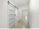 Bright hallway features a sliding barn door, neutral tile flooring, and leads to other rooms at 5226 Mahogany Dr, Mount Dora, FL 32757