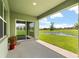 Covered patio provides outdoor living space with a serene view of the lake and manicured lawn at 5226 Mahogany Dr, Mount Dora, FL 32757